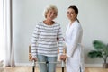 Elderly woman holding rollator feels satisfied after therapy with physiotherapist