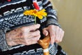 An elderly woman holding a yellow flower and a wooden cane on a summer day on the porch