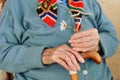 An elderly woman holding flowers and a wooden cane in the street. Royalty Free Stock Photo