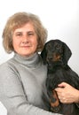 Elderly woman holds black and tan dachshund in her arms