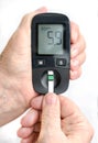 An elderly woman holds a glucometer in her hands and wants to do a blood test for sugar