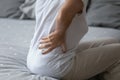 Elderly woman holds hand in lumbar feels severe backpain closeup