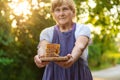 An elderly woman holds honey in her hands, selective focus.