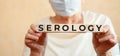 Elderly woman holds wooden cubes in her hands with the inscription SEROLOGY