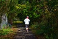 Elderly Woman Jogging Through A Path In A Park