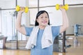 Elderly woman lifting two dumbbells in gym center Royalty Free Stock Photo