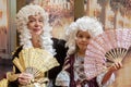 An elderly woman and a little girl dressed in elegant 18th century style clothing pose with hand fans at a costumed Royalty Free Stock Photo