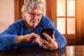 Elderly woman looking at camera while using mobile phone. Happy smiling grandma Royalty Free Stock Photo