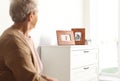 Elderly woman looking at framed family portraits