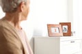 Elderly woman looking at framed  portraits indoors Royalty Free Stock Photo