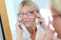 Elderly woman looking in the mirror trying on eyeglasses