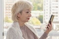 An elderly woman looks carefully at her mobile phone.Maybe she can`t see well or is thinking of taking the call or not Royalty Free Stock Photo