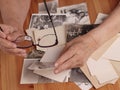 An elderly woman looks at old photographs, recalls her past youth. Hands on the table. Loneliness,, memories Royalty Free Stock Photo