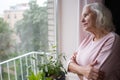 An elderly woman looks sadly out the window. Royalty Free Stock Photo