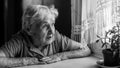 An elderly woman looks sadly out the window. Loneliness Royalty Free Stock Photo