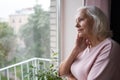 An elderly woman looks sadly out the window. Royalty Free Stock Photo