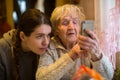 Elderly woman looks at a smartphone, with his adult granddaughter Royalty Free Stock Photo