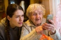 An elderly woman looks at a smartphone his adult granddaughter Royalty Free Stock Photo