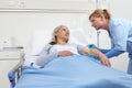 Elderly woman lying in the hospital room bed, nurse disinfect the patient`s arm to injects the vaccine Royalty Free Stock Photo