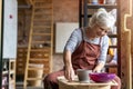 Elderly woman making ceramic work with potter`s wheel Royalty Free Stock Photo