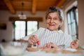 Elderly woman making and decorating cakes in a kitchen at home. Copy space.