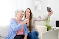 Elderly woman making selfie with her young granddaughter at home