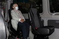 Elderly woman in a medical mask, in a car for transportation of disabled people, the concept of transportation of