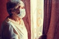 An elderly woman in medical mask stay isolation at home for self quarantine