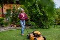 Elderly woman mowing grass with lawn mower in the garden, garden work concept. Royalty Free Stock Photo