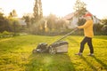 Young woman cutting grass with a lawn mower. Outdoor household chores concept. Royalty Free Stock Photo