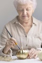 An elderly woman paints a pumpkin. Lifestyle pensioners. Old hands paint pumpkin with gold paint with brush