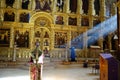 Elderly woman in a peaceful pose, in prayer as she kneels in front of a golden altar in a religious