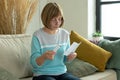 An elderly woman with pills reads the instructions at home sitting on the couch Royalty Free Stock Photo