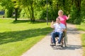 Elderly woman in pink blouse pushes wheel chair Royalty Free Stock Photo