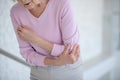 Elderly woman in pink shirt suffering from pain in elbow