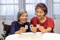 Elderly woman playing alphabet games for improve mental health and memory with daughter