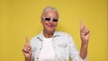 An elderly woman points her finger to attract attention on a beige background