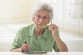 Elderly woman portrait holding glasses and doing crossword Royalty Free Stock Photo