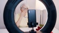 Elderly woman presenting make up. Recording on smartphone or having a video call. Red roses on the table. Valentines day Royalty Free Stock Photo