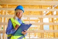 Elderly woman with protective helmet and yellow vest working as an engineer, doing expertise at construction of