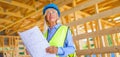 Elderly woman with protective helmet and yellow vest working as an engineer, doing expertise at construction of