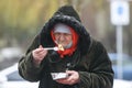 Elderly woman in a protective mask against coronavirus Covid 19 eats on the street in Kyiv, Ukraine. January 2021
