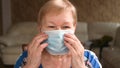 Elderly woman puts on a face protective mask. Life during a pandemic and quarantine