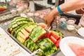 An elderly woman puts a plate of slices of ripe watermelon Royalty Free Stock Photo