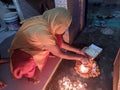 Elderly woman is putting a few pieces of some sweets as a part of Hindu prayers