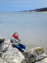 Woman Reading a Book On Beach Rocks