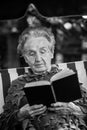 Elderly only woman reading a book sitting in a hammock. Royalty Free Stock Photo