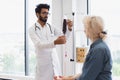 Elderly woman receiving blood transfusion looking at medical doctor.