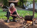 Elderly woman roasting coffee manually, just like she did on the farm