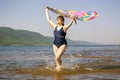 elderly woman runs along the waves on a summer sunny day against the background of mountains Royalty Free Stock Photo